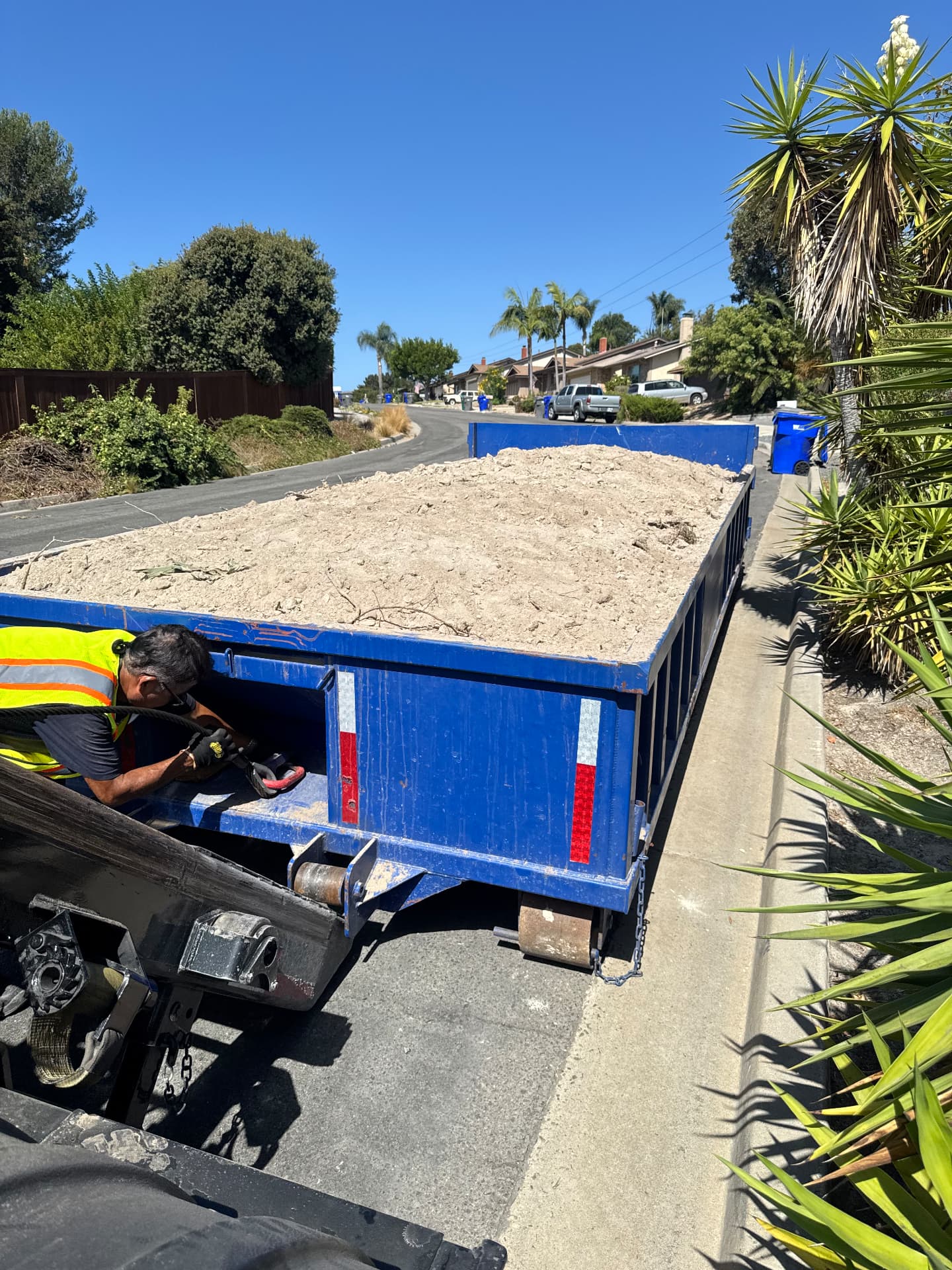 Blue 10-yard lowboy dumpster loaded with dirt